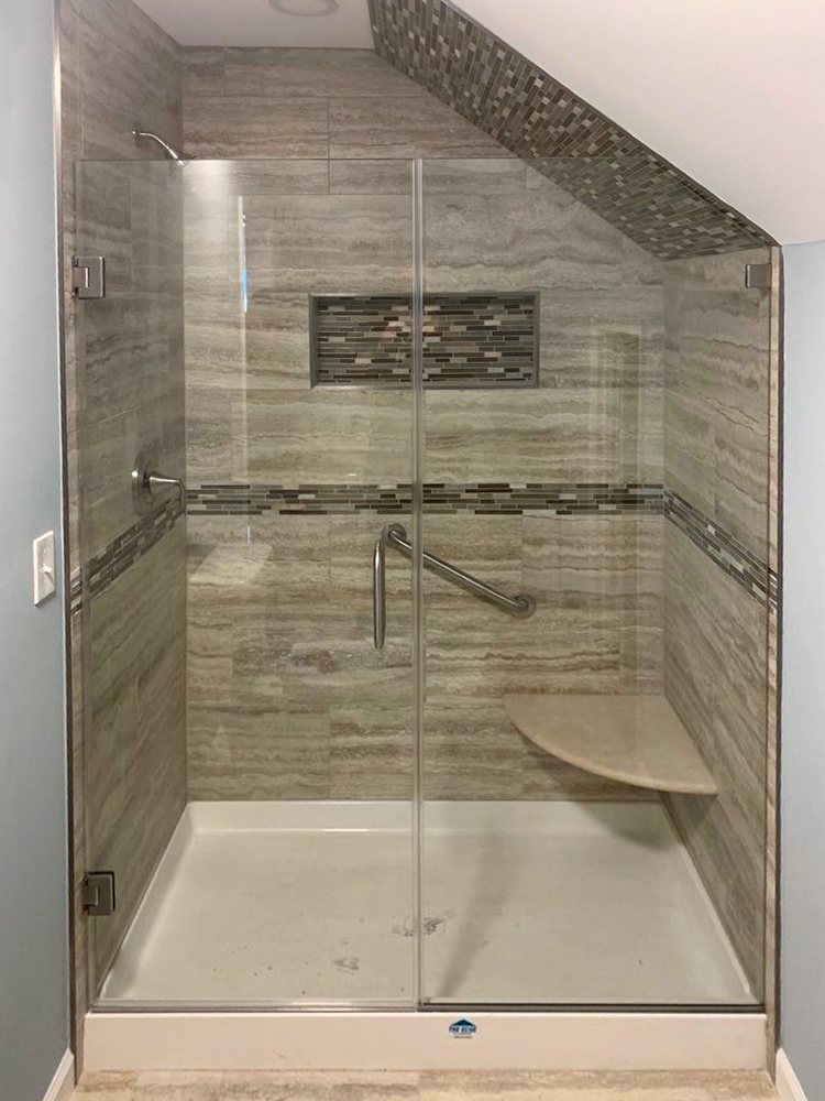 Custom glass shower enclosure cut to fit under a sloped ceiling