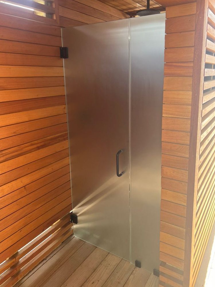 Frosted glass shower enclosure against warm wood walls